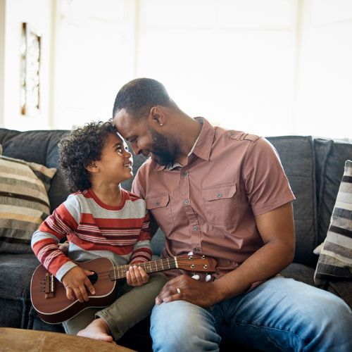 child holding ukulele face to face with a man  
